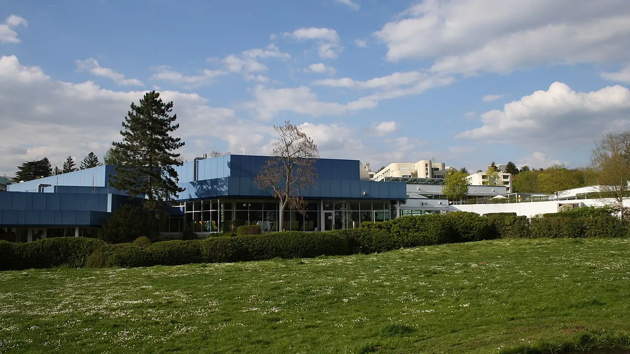 Blau verkleidetes Gebäude des Thermalbads Aukammtal in Wiesbaden mit Glasfront hinter einer Wiese